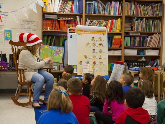 Student reading to a classroom full of elementary school children.