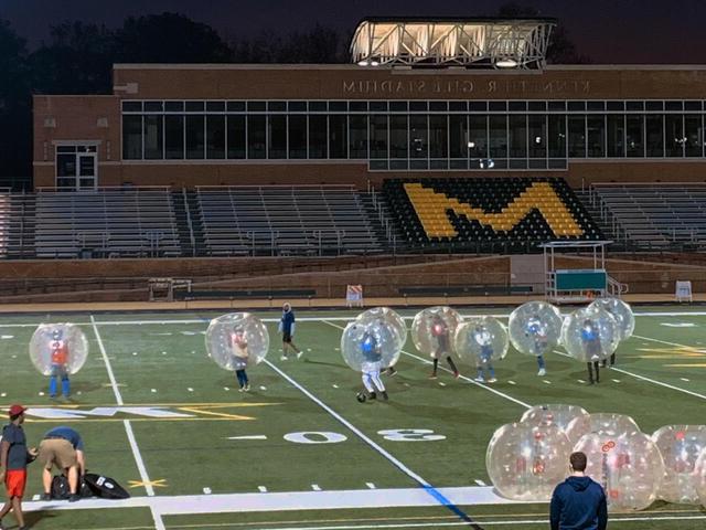 图为，10名学生在吉尔体育场的足球场上，戴着巨大的充气球玩泡泡足球. 