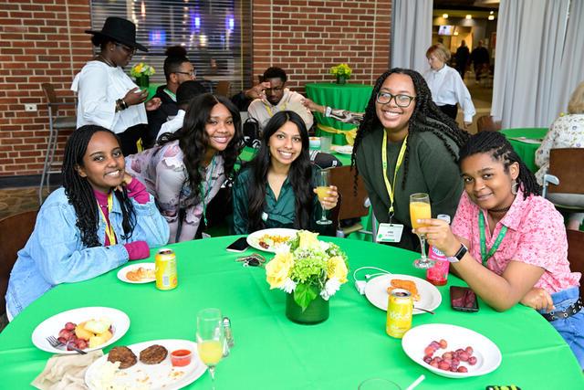 在2022年返校节期间，一群妇女坐在一张桌子旁吃DEI早午餐.